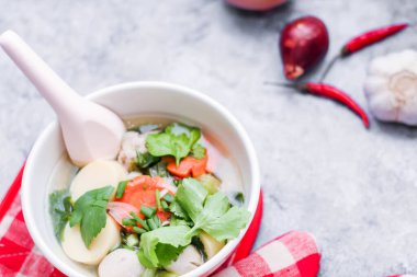 Beyaz bardaklarda servis edilen haşlanmış tofu ve kıymalı domuz eti ile beyaz masaya yerleştirilmiş kırmızı kareli çay tabakları..