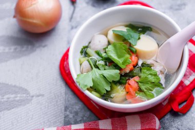 Beyaz bardaklarda servis edilen haşlanmış tofu ve kıymalı domuz eti ile beyaz masaya yerleştirilmiş kırmızı kareli çay tabakları..