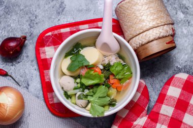 Beyaz bardaklarda servis edilen haşlanmış tofu ve kıymalı domuz eti ile beyaz masaya yerleştirilmiş kırmızı kareli çay tabakları..