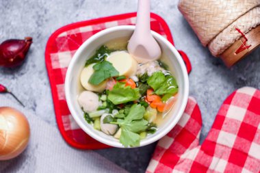 Beyaz bardaklarda servis edilen haşlanmış tofu ve kıymalı domuz eti ile beyaz masaya yerleştirilmiş kırmızı kareli çay tabakları..