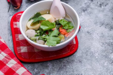 Beyaz bardaklarda servis edilen haşlanmış tofu ve kıymalı domuz eti ile beyaz masaya yerleştirilmiş kırmızı kareli çay tabakları..