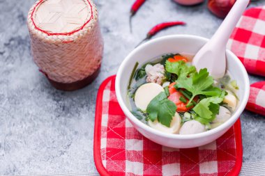 Beyaz bardaklarda servis edilen haşlanmış tofu ve kıymalı domuz eti ile beyaz masaya yerleştirilmiş kırmızı kareli çay tabakları..