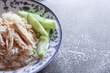 Çin usulü bir yemekle servis edilen tavuk çorbası ile buğulanmış pirinç soya sosu ve et suyu gri bir masada servis edilir..