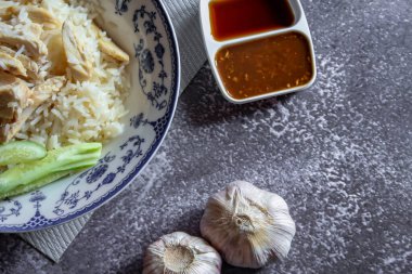 Çin usulü bir tabakta servis edilen Çin usulü tavuklu pilav. Soya sosu ve et suyu gri bir masada..