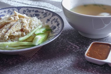 Çin usulü bir tabakta servis edilen tavuk çorbasıyla buğulanmış pirinç soya sosu ve gri bir masada çorba.