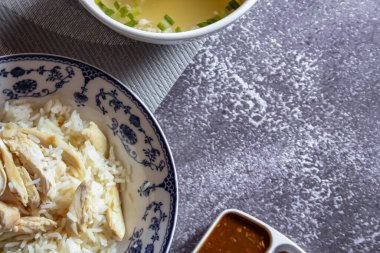 Çin usulü bir tabakta servis edilen Çin usulü tavuklu pilav. Soya sosu ve et suyu gri bir masada..