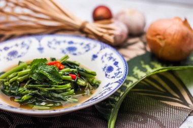 Çin desenli bir tabakta servis edilen yeşil yapraklar, soğanlar ve soğan aromalı soya fasulyesi ezmesiyle Kızarmış Sabah Zaferi..