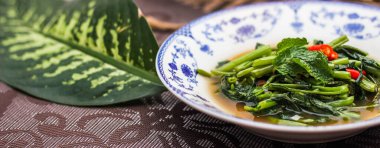 Çin desenli bir tabakta servis edilen yeşil yapraklar, soğanlar ve soğan aromalı soya fasulyesi ezmesiyle Kızarmış Sabah Zaferi..