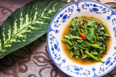 Çin desenli bir tabakta servis edilen yeşil yapraklar, soğanlar ve soğan aromalı soya fasulyesi ezmesiyle Kızarmış Sabah Zaferi..