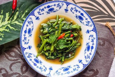 Çin desenli bir tabakta servis edilen yeşil yapraklar, soğanlar ve soğan aromalı soya fasulyesi ezmesiyle Kızarmış Sabah Zaferi..