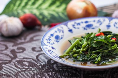 Çin desenli bir tabakta servis edilen yeşil yapraklar, soğanlar ve soğan aromalı soya fasulyesi ezmesiyle Kızarmış Sabah Zaferi..