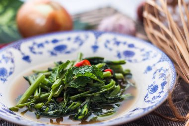 Çin desenli bir tabakta servis edilen yeşil yapraklar, soğanlar ve soğan aromalı soya fasulyesi ezmesiyle Kızarmış Sabah Zaferi..