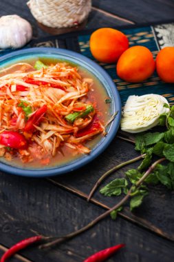 Baharatlı papaya salatası mavi bir tabakta, kovada pilav ve uzun fasulye, kurutulmuş kırmızı biber ve sebze ile servis edilir..