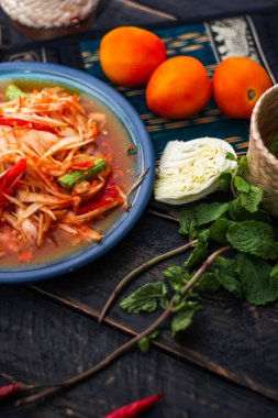 Baharatlı papaya salatası mavi bir tabakta, kovada pilav ve uzun fasulye, kurutulmuş kırmızı biber ve sebze ile servis edilir..