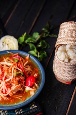 Baharatlı papaya salatası mavi bir tabakta, kovada pilav ve uzun fasulye, kurutulmuş kırmızı biber ve sebze ile servis edilir..