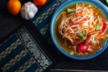 Baharatlı papaya salatası mavi bir tabakta, kovada pilav ve uzun fasulye, kurutulmuş kırmızı biber ve sebze ile servis edilir..