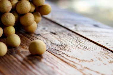 Bir grup Longan, arkasında yeşil yapraklar olan ahşap bir masaya yerleştiriliyor..