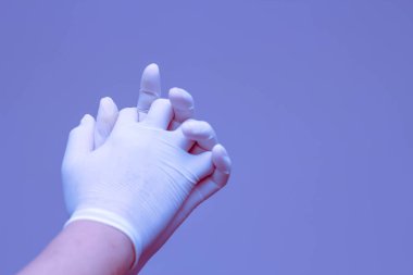 Lastik eldiven takan eller mavi arka planda el ele tutuşmayı sembolize eder..