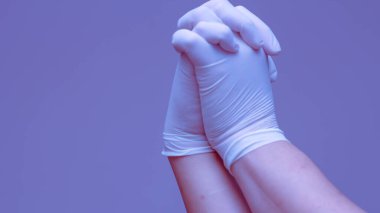 Lastik eldiven takan eller mavi arka planda el ele tutuşmayı sembolize eder..