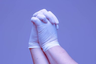 Lastik eldiven takan eller mavi arka planda el ele tutuşmayı sembolize eder..