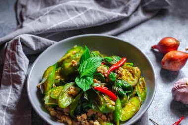 Kızarmış patlıcanla domuz etini yeşil bir tabakta masanın üstünde kurutulmuş sarımsaklı biberle karıştırın.