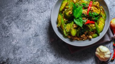 Kızarmış patlıcanla domuz etini yeşil bir tabakta masanın üstünde kurutulmuş sarımsaklı biberle karıştırın.