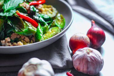 Kızarmış patlıcanla domuz etini yeşil bir tabakta masanın üstünde kurutulmuş sarımsaklı biberle karıştırın.