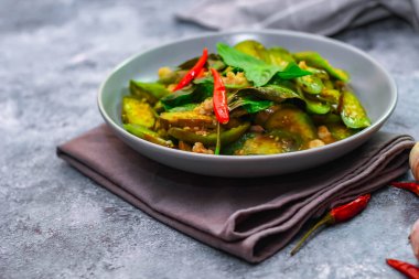 Kızarmış patlıcanla domuz etini yeşil bir tabakta masanın üstünde kurutulmuş sarımsaklı biberle karıştırın.