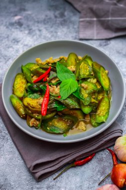Kızarmış patlıcanla domuz etini yeşil bir tabakta masanın üstünde kurutulmuş sarımsaklı biberle karıştırın.