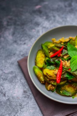 Kızarmış patlıcanla domuz etini yeşil bir tabakta masanın üstünde kurutulmuş sarımsaklı biberle karıştırın.