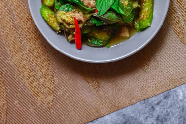 Kızarmış patlıcanla domuz etini yeşil bir tabakta masanın üstünde kurutulmuş sarımsaklı biberle karıştırın.