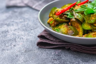 Kızarmış patlıcanla domuz etini yeşil bir tabakta masanın üstünde kurutulmuş sarımsaklı biberle karıştırın.