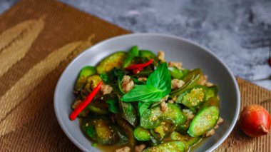 Kızarmış patlıcanla domuz etini yeşil bir tabakta masanın üstünde kurutulmuş sarımsaklı biberle karıştırın.