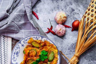 Kızarmış Solanum melongena, yeşil bir tabakta yumurta ve yanında sarımsaklı, kurutulmuş kırmızı biber.