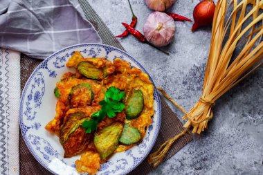 Kızarmış Solanum melongena, yeşil bir tabakta yumurta ve yanında sarımsaklı, kurutulmuş kırmızı biber.
