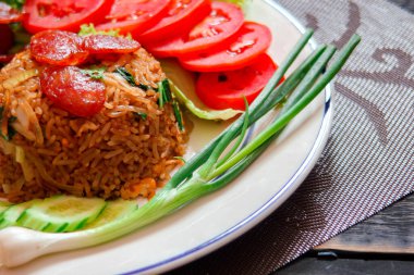 Kızarmış pilav ve Çin sosisi kızarmış yumurta, domates ve marul ile servis edilir..