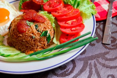 Kızarmış pilav ve Çin sosisi kızarmış yumurta, domates ve marul ile servis edilir..