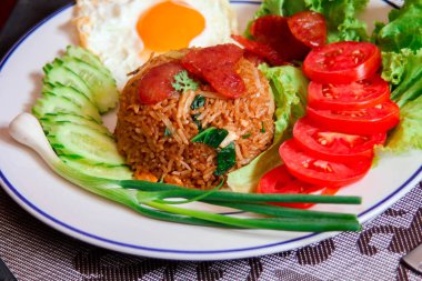 Kızarmış pilav ve Çin sosisi kızarmış yumurta, domates ve marul ile servis edilir..