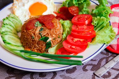 Kızarmış pilav ve Çin sosisi kızarmış yumurta, domates ve marul ile servis edilir..