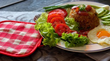 Kızarmış pilav ve Çin sosisi kızarmış yumurta, domates ve marul ile servis edilir..