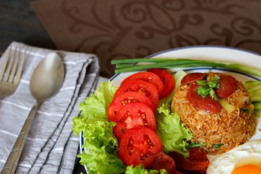 Kızarmış pilav ve Çin sosisi kızarmış yumurta, domates ve marul ile servis edilir..