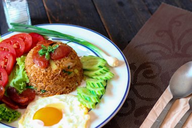 Kızarmış pilav ve Çin sosisi kızarmış yumurta, domates ve marul ile servis edilir..