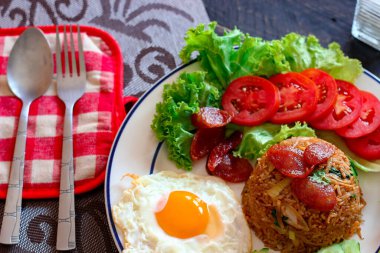 Kızarmış pilav ve Çin sosisi kızarmış yumurta, domates ve marul ile servis edilir..
