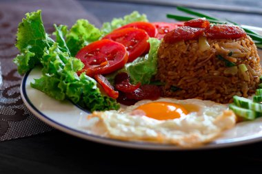 Kızarmış pilav ve Çin sosisi kızarmış yumurta, domates ve marul ile servis edilir..