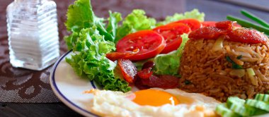 Kızarmış pilav ve Çin sosisi kızarmış yumurta, domates ve marul ile servis edilir..
