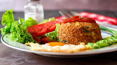 Kızarmış pilav ve Çin sosisi kızarmış yumurta, domates ve marul ile servis edilir..