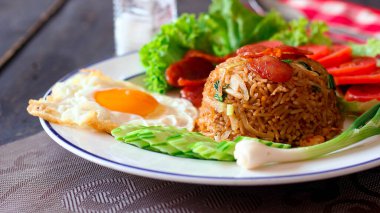 Kızarmış pilav ve Çin sosisi kızarmış yumurta, domates ve marul ile servis edilir..