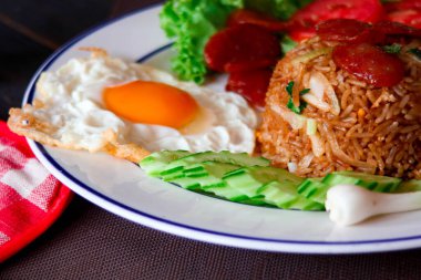 Kızarmış pilav ve Çin sosisi kızarmış yumurta, domates ve marul ile servis edilir..