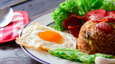 Kızarmış pilav ve Çin sosisi kızarmış yumurta, domates ve marul ile servis edilir..