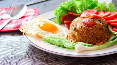 Kızarmış pilav ve Çin sosisi kızarmış yumurta, domates ve marul ile servis edilir..